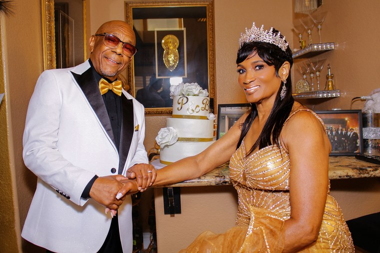 Couple holding a cake knife beside their white and gold wedding cake