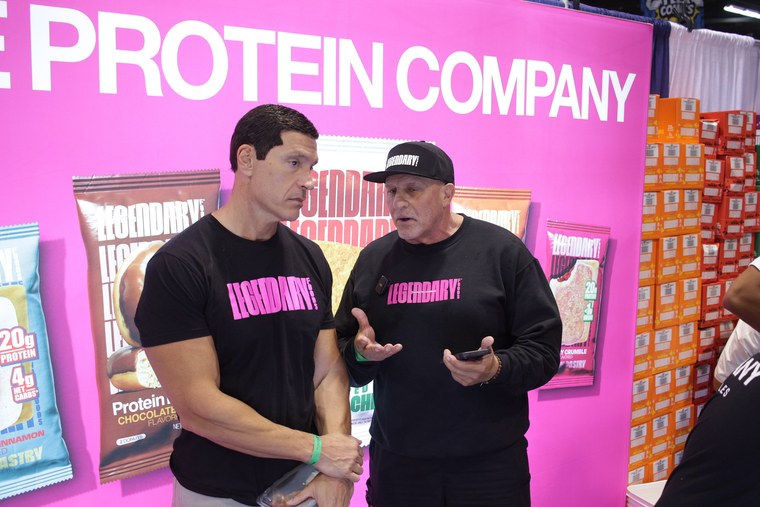 Two Legendary Foods representatives in conversation at a pink branded booth