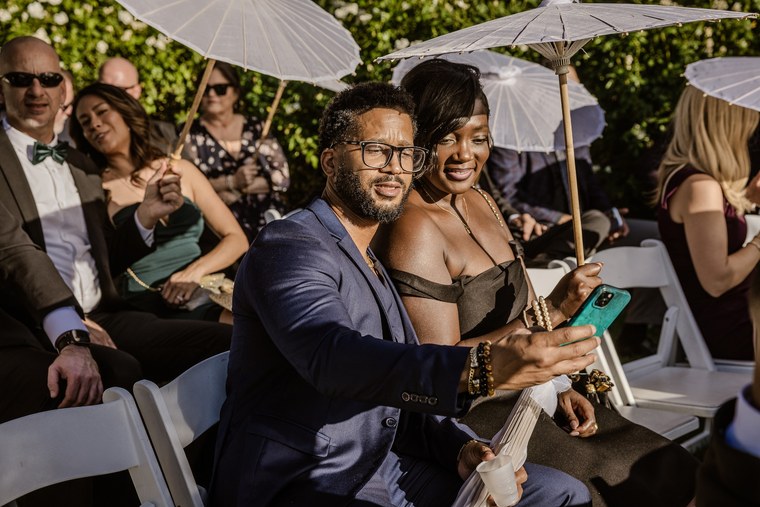 Wedding guests taking a selfie beneath white parasols