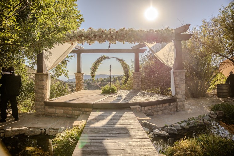 Sunlit outdoor ceremony pergola with flowers and mountain views