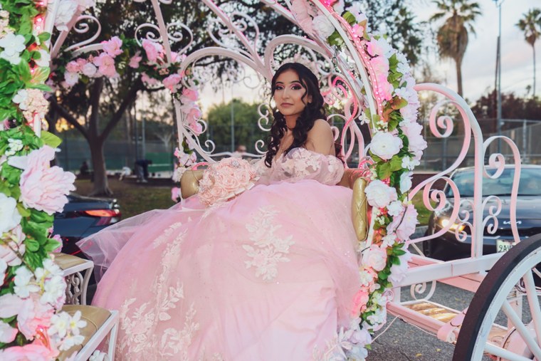 Celebrant in a pink gown seated in a flower-covered carriage
