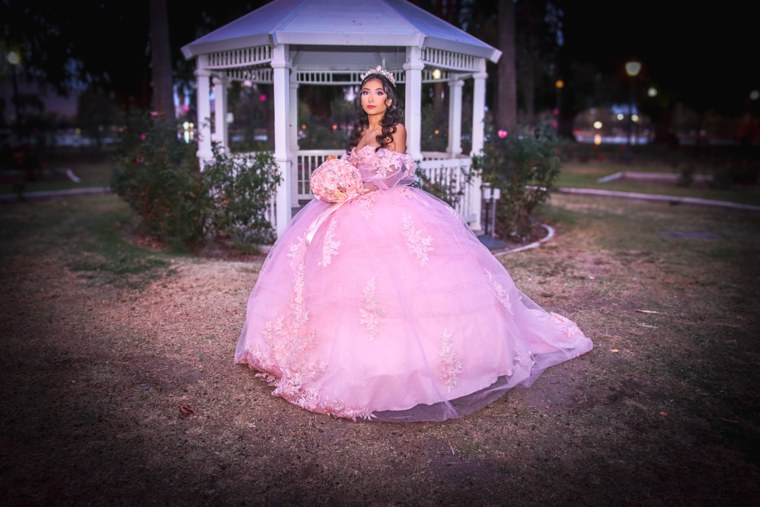 Full-length portrait of a celebrant in a pink gown beside a white gazebo