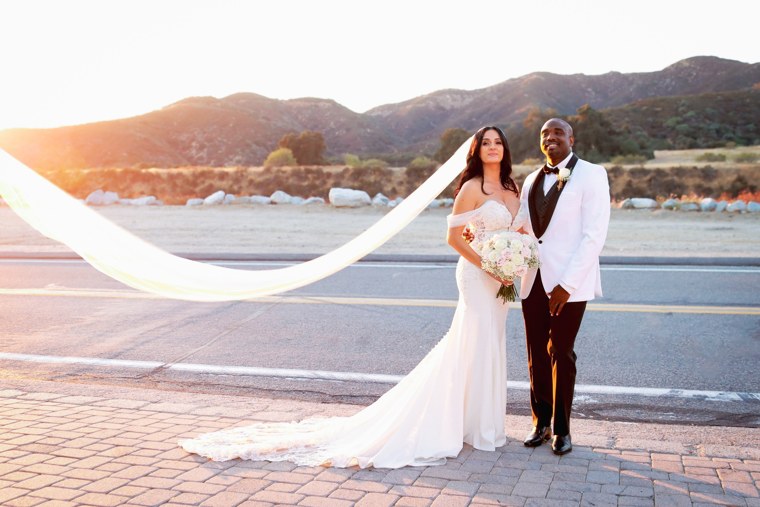 Newlyweds at sunset with a flowing veil and mountain backdrop
