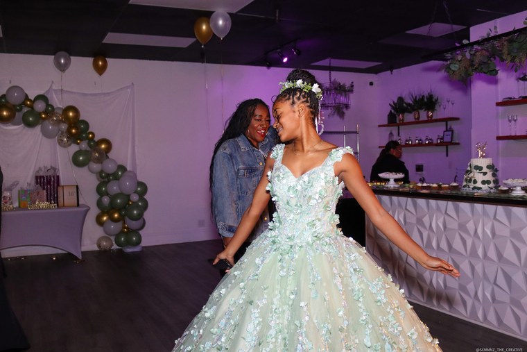 Sweet 16 celebrant dancing with a guest under purple reception lights