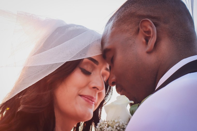 Bride and groom touching foreheads beneath a translucent veil